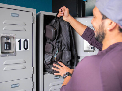 Guest storing a backpack in a secure locker at California Dreams Hostel