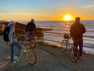 Travelers with bikes watching the sunset by the ocean in San Diego