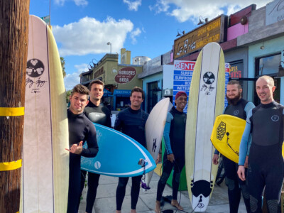 Group of travelers with surfboards outside a surf rental shop in San Diego