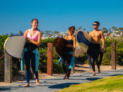 Travelers carrying surfboards near the beach in San Diego